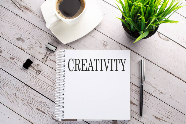Cofee cup, notepad,pen on wooden background. Business concept. Text CREATIVITY - Foto, Imagem