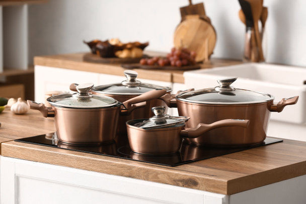 Glänzende Kupferkochtöpfe auf Herd in Küche - Foto, Bild