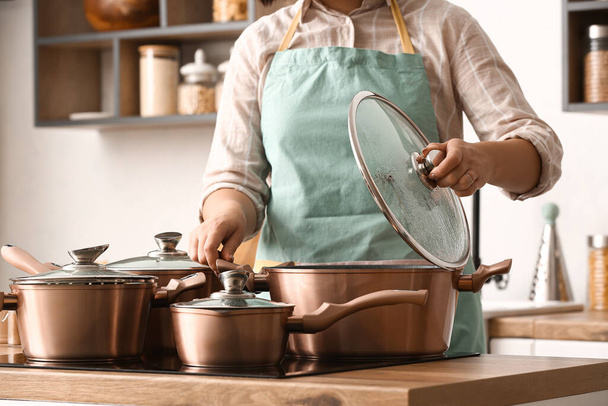 Femme avec des casseroles en cuivre cuisine - Photo, image