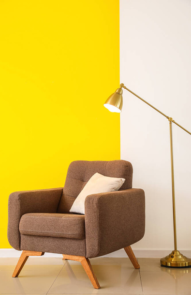 Goldene Stehlampe und Sessel in der Nähe der Wand - Foto, Bild