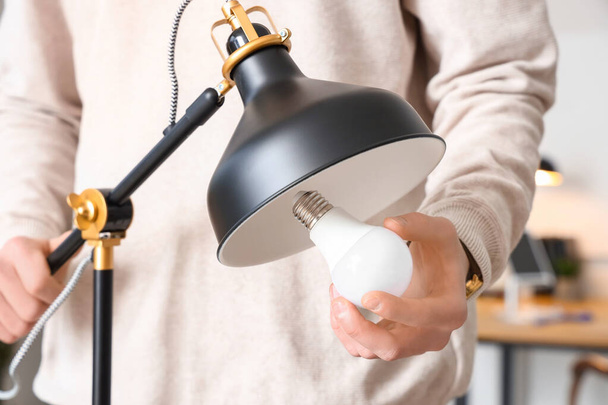 Homme changeant ampoule dans la lampe de bureau, gros plan - Photo, image