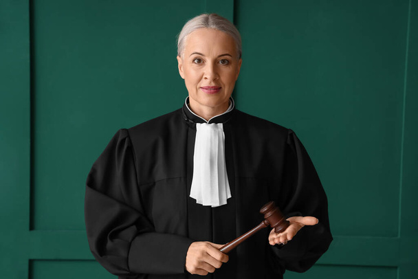 Femme juge mature avec marteau sur fond vert - Photo, image