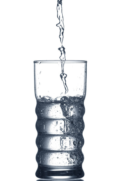 Pouring of clear water in glass isolated on white - Photo, Image
