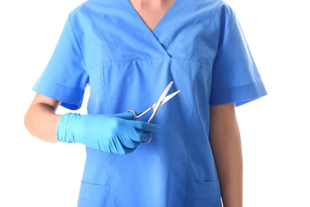 Female doctor with medical scissors on white background - Fotoğraf, Görsel