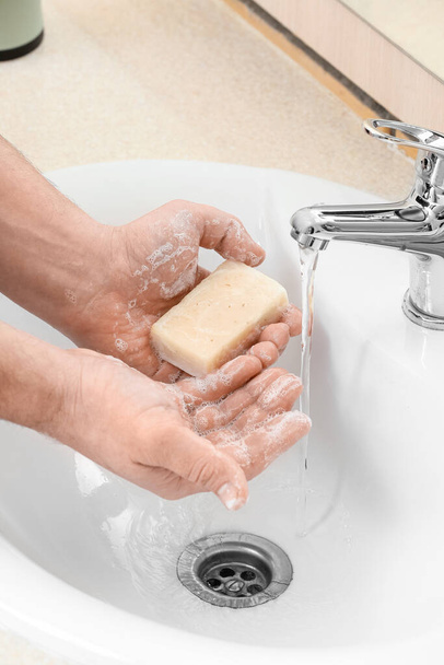 Ο άνθρωπος πλένει τα χέρια του με σαπούνι σε κεραμικό νεροχύτη, κοντινό πλάνο - Φωτογραφία, εικόνα