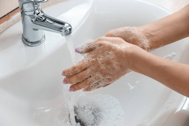 Frau wäscht sich die Hände mit Schaum in Keramikspüle, Nahaufnahme - Foto, Bild