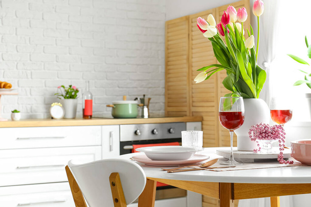 Eettafel met setting en glazen wijn voor Internationale Vrouwendag viering in keuken - Foto, afbeelding