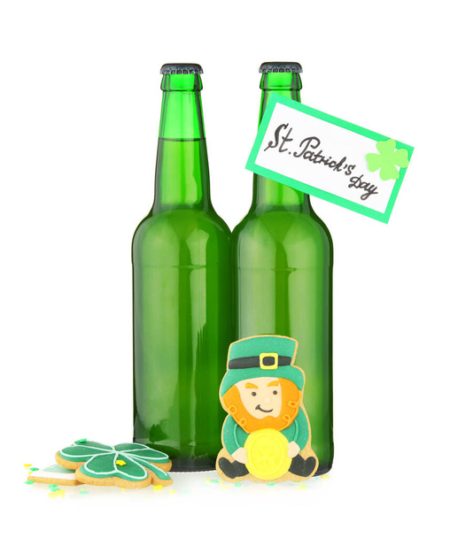 Bottles of beer, gingerbread cookies and card for St. Patrick's Day celebration on white background - Photo, Image
