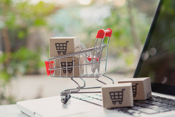 Shopping online. Cardboard box with a shopping cart logo in a trolley on laptop keyboard. Shopping service on The online web. offers home deliver - Photo, Image