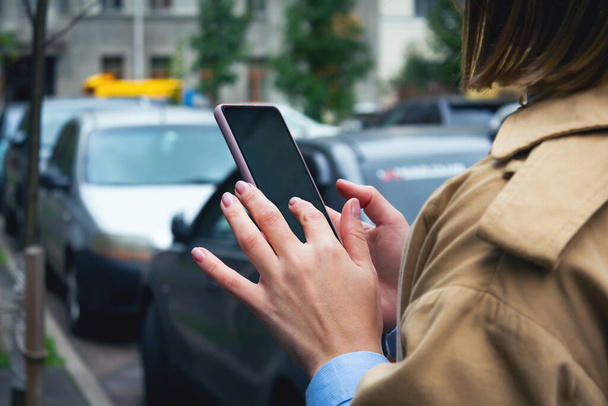 Woman holding mobile phone in hands. Carsharing.  - Φωτογραφία, εικόνα