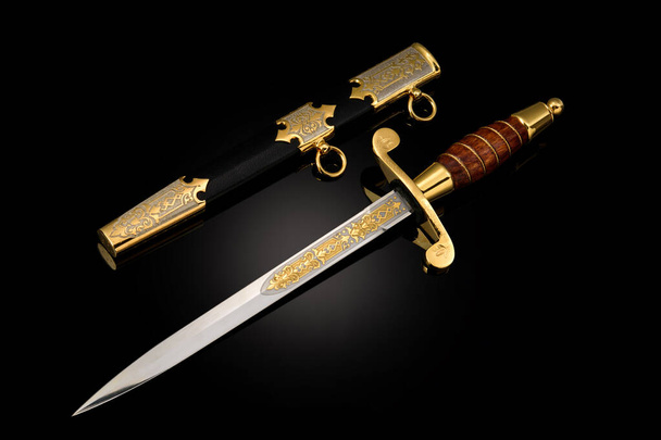 suvenýr sbírkový stříbrný zlatý nůž s pochvou, s kovovou rytinou, na černém pozadí. Luxusní zbraně s tradičními vzory ve středověkém stylu. - Fotografie, Obrázek