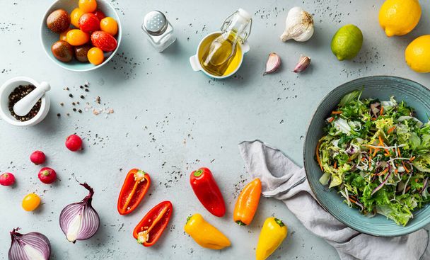 Fresh raw ingredients for colorful spring vegetable salad with cherry tomatoes and peppers. Healthy organic vegan lunch. Kitchen worktop from above (top view). Background with free copy space. - Foto, imagen