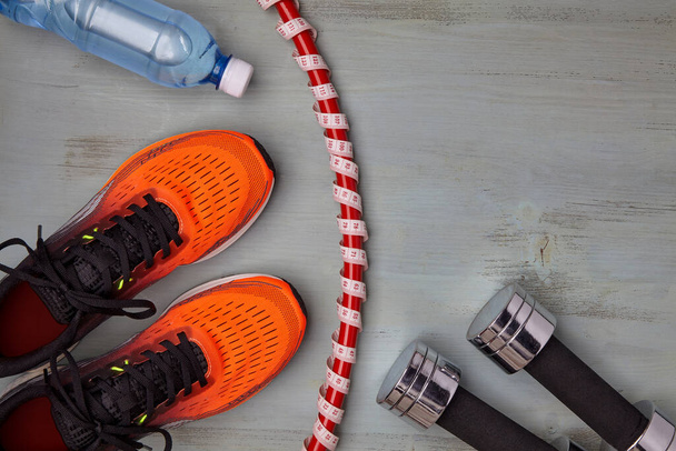 Orange sneakers, a plastic bottle of water and metal dumbbells - Photo, Image