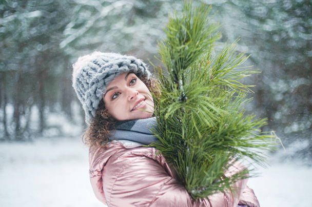 Beautiful smiling woman with pine tree has fun outdoors. Woman in snowy forest. Winter vacation. - Photo, Image