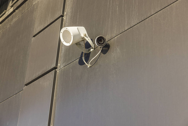 Widok z bliska na zewnętrzną lampę oświetleniową i kamerę bezpieczeństwa publicznego na szarej ścianie. Szwecja.  - Zdjęcie, obraz