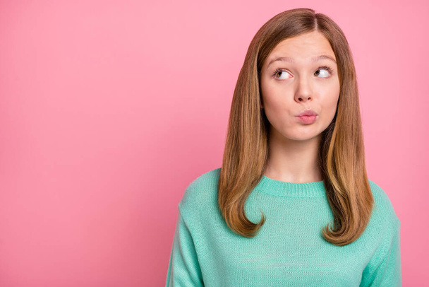 Photo of doubtful school girl dressed teal pullover looking empty space isolated pink color background - 写真・画像