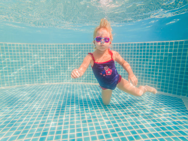 The little girl in the water park swimming underwater and smiling - Фото, зображення
