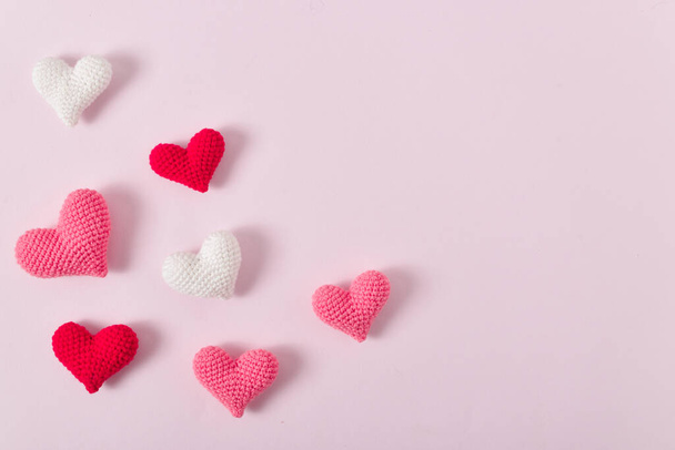 Background with pink knitted hearts for a festive Valentine's Day. Banner for February 14. Greeting card with hearts. Space for copying. Flat position, top view. - Фото, зображення