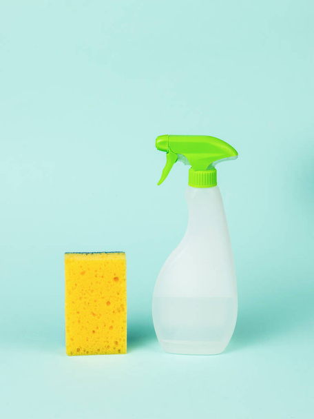 Uma garrafa de plástico com agente de limpeza e uma esponja de espuma sobre um fundo azul. Kit de limpeza. - Foto, Imagem