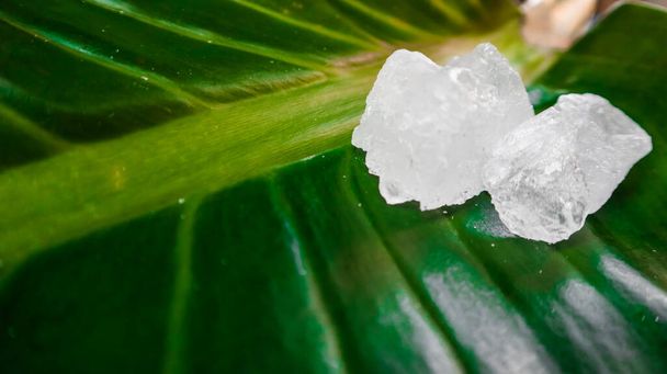 Crystal clear alum cubes or Potassium alum on green leaf. Chemical compound substance. Concept for beauty , spa and underarm treatment industrial.  - Photo, Image