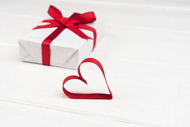 Valentines Day or birthday concept with copy space. Red ribbon heart and gift box on white wood - Fotografie, Obrázek