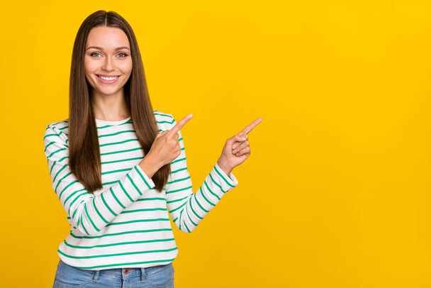 Photo of cute sweet woman wear striped shirt pointing fingers empty space isolated yellow color background - Фото, изображение