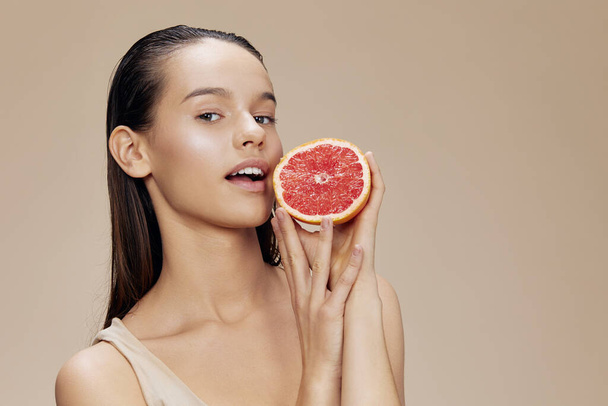 brunette grapefruit vitaminen gezondheid cosmetologie beige achtergrond - Foto, afbeelding