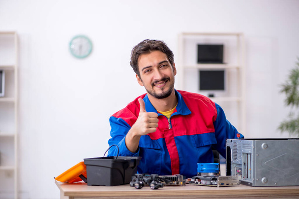Bilgisayar tamir eden genç bir erkek tamirci. - Fotoğraf, Görsel