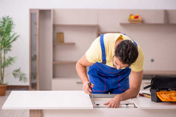 Genç erkek marangoz evdeki masayı onarıyor. - Fotoğraf, Görsel