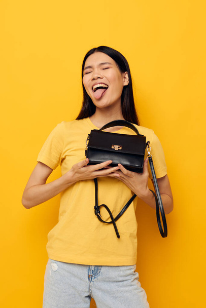 Charming young Asian woman with a black womans bag in her hands Lifestyle unaltered - Valokuva, kuva