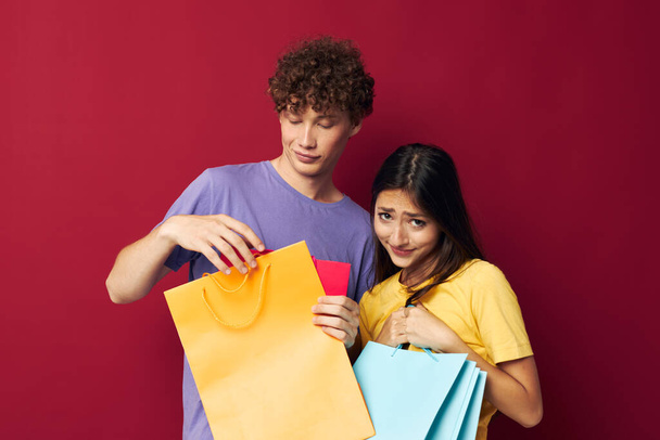 portret van een man en een vrouw kleurrijke tassen winkelen plezier rode achtergrond ongewijzigd - Foto, afbeelding