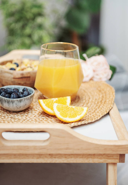 Zdrowe śniadanie. Sok pomarańczowy, owoce i miska z granolą na tacy. Śniadanie do łóżka.  - Zdjęcie, obraz