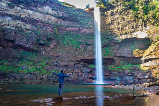 junger Mann am Wasserfall fallende Bäche von Berggipfel mit Reflexion aus verschiedenen Perspektiven Bild aufgenommen auf phe phe fall meghalaya indien. er ist einer der höchsten wasserfälle von meghalaya. - Foto, Bild