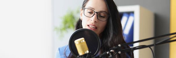 Young beautiful woman speaks into microphone at workplace - Фото, зображення