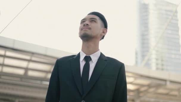 Ελκυστικός ασιάτης επιχειρηματίας με μαύρο κοστούμι που σκέφτεται μελλοντικά επιχειρηματικά σχέδια ενώ στέκεται έξω στο δρόμο urban. - Πλάνα, βίντεο