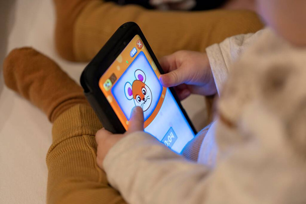 Brecht, Belgio - 7 novembre 2021: Ritratto di un bambino che gioca a un'app per videogiochi su uno smartphone Samsung Android. Il bambino sta tenendo il dispositivo nelle sue mani e sta usando le dita per giocare. - Foto, immagini