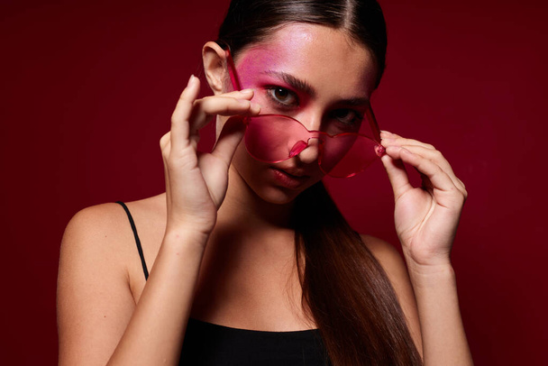 Portrait of beautiful young woman in pink glasses makeup emotions cosmetics close-up unaltered - Fotó, kép