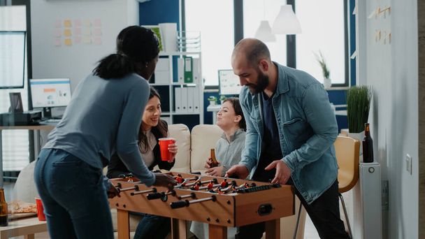 Diverse group of workmates enjoying game with foosball table - Fotografie, Obrázek