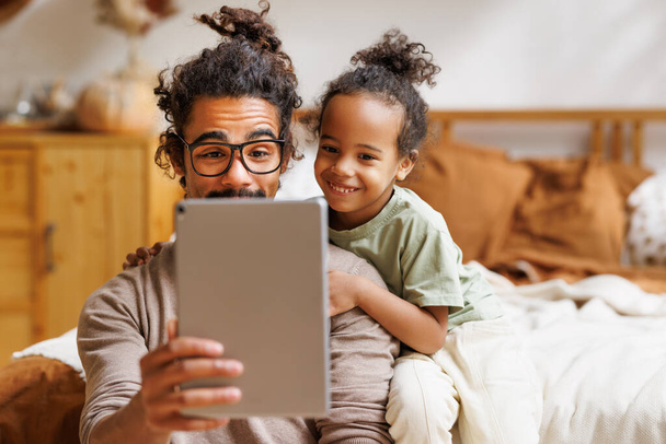 Щаслива афро-американська сім'я маленький син з татом дивляться смішні відео на планшеті разом вдома. - Фото, зображення