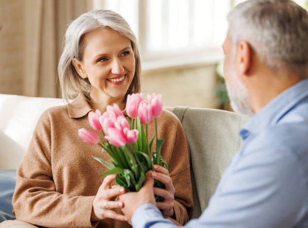 Счастливая пожилая женщина получает романтический подарок букет тюльпанов от любящего мужа на День Святого Валентина - Фото, изображение
