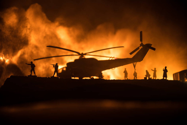 A katonai helikopter sziluettje készen áll a harci zónából való repülésre. Díszített éjszakai felvétel helikopterrel kezdődik a sivatagban ködös tónusú háttérvilágítással. Szelektív fókusz. Háborús koncepció - Fotó, kép