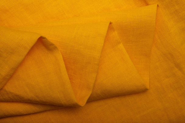 Ryppyinen pellavakangas taitettu lautasliinat. Luonnollinen pellavakangas rakenne. Kuvioitu keltainen kangas tausta. Ympäristöystävällisen materiaalin käytön käsite - Valokuva, kuva