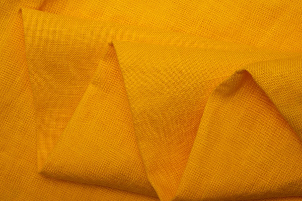 Serviettes pliées en tissu de lin froissé. Texture tissu lin naturel. Texturé fond de tissu jaune. Concept d'utilisation de matériaux naturels respectueux de l'environnement - Photo, image
