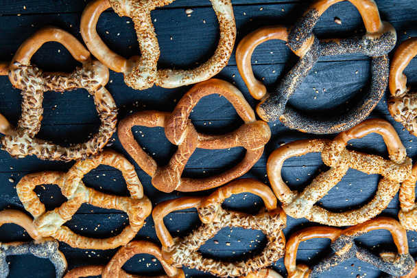 Preparados frescos caseiros pretzels macios. Diferentes tipos de bagels assados com sementes em um fundo preto. - Foto, Imagem