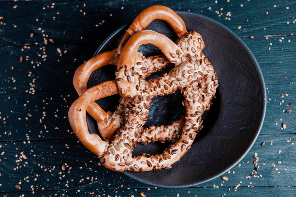 Fresh prepared homemade soft pretzels. Different types of baked bagels with seeds on a black background. - Photo, Image
