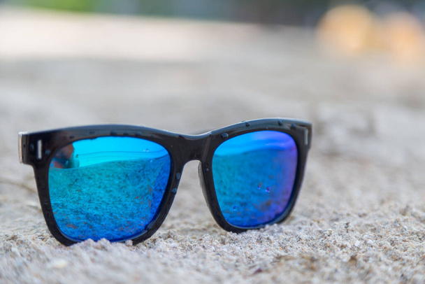 Gafas de sol azules sobre fondo de arena blanca - Foto, imagen