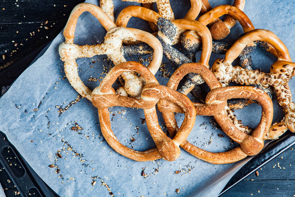 Preparados frescos caseiros pretzels macios. Diferentes tipos de bagels assados com sementes em um fundo preto. - Foto, Imagem