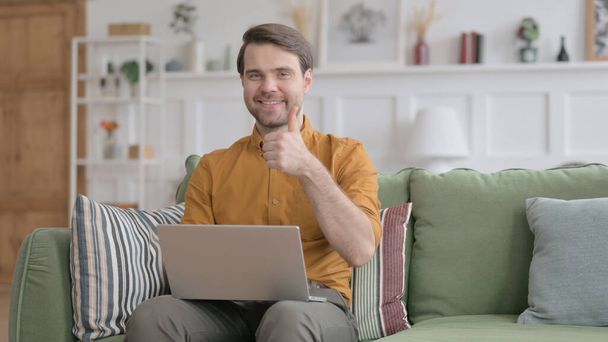 Young Man Showing Thumbs Up Sign While using Laptop in Office - Photo, Image