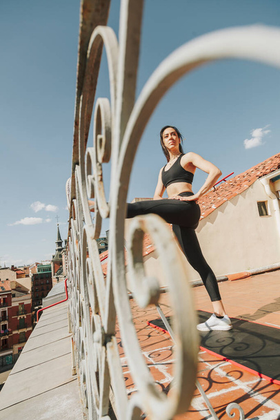 Sportieve vrouw die zich uitstrekt op een dak. Levensstijl in de gezondheidszorg. - Foto, afbeelding