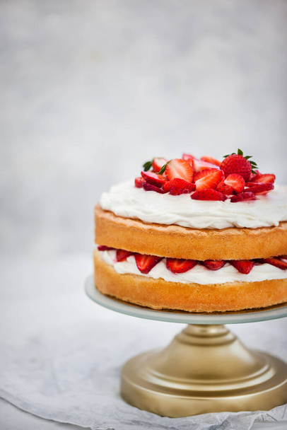 Губний торт Вікторії, смачний домашній ванільний торт, прикрашений збитими вершками та свіжою полуницею, на білому
 - Фото, зображення
